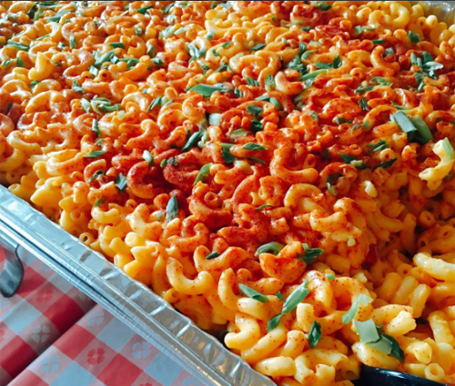 Large aluminum container of mac and cheese seasoned with paprika and shallots