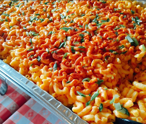 Large aluminum container of mac and cheese seasoned with paprika and shallots